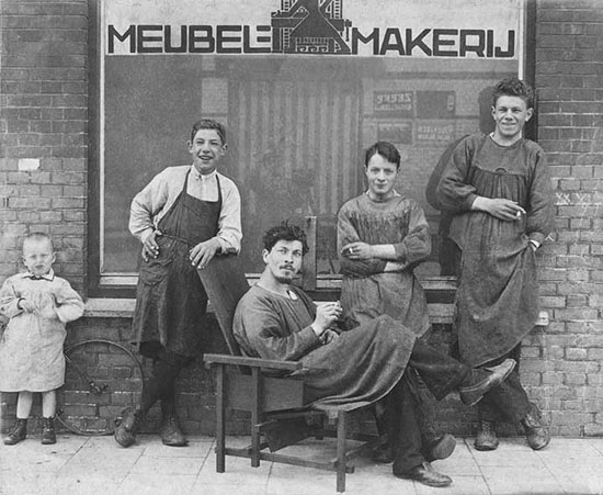 Ritveld ispred svoje radionice 1919. godine (sedi na Crveno plavoj stolici)
